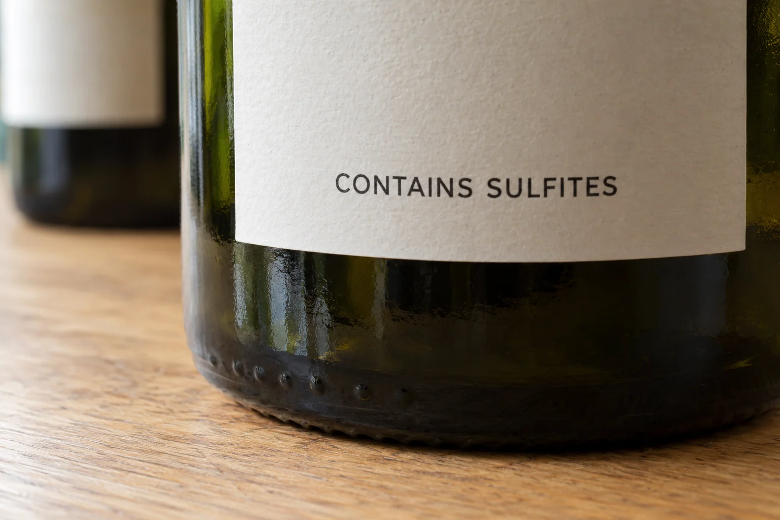 Close view of CONTAINS SULFITES printed on a cream back label on a green wine bottle