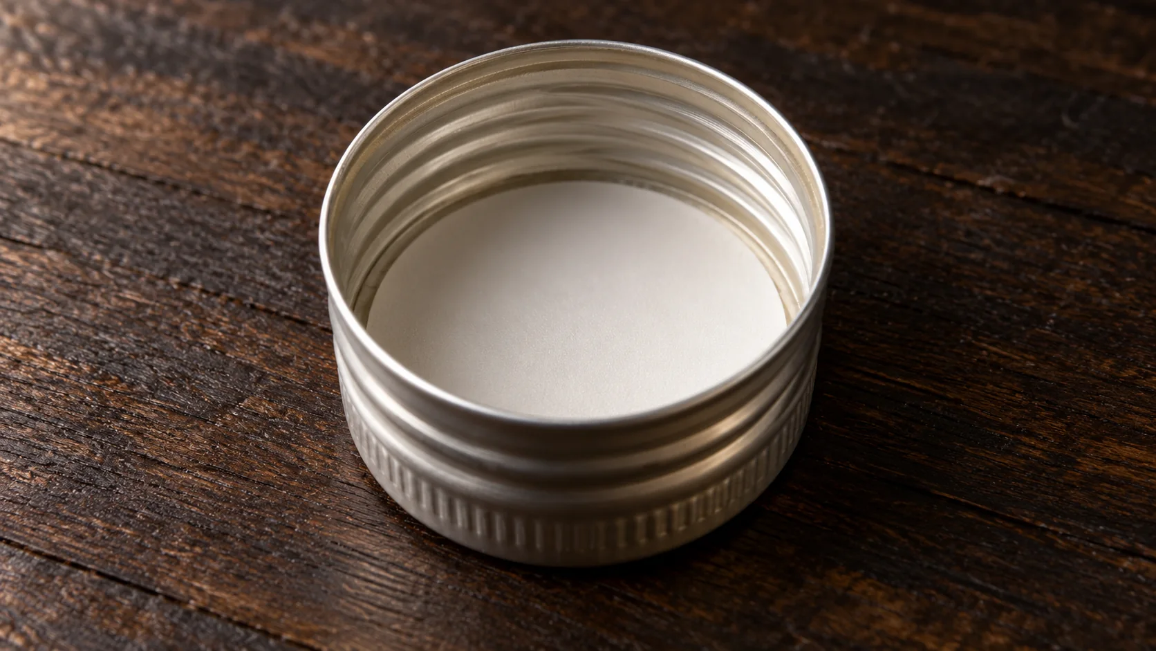 Close view of a plain liner disc inside an unlabeled aluminum screw cap